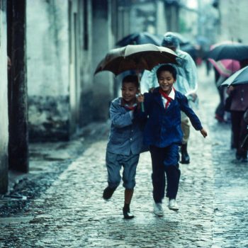 Young boys running with umbrella in rain, Suzchou, China