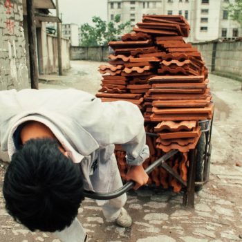 Man pulling heavy load of red tiles, Suzchou, China