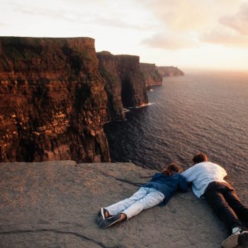 Couple looking over edge at Cliffs of Moher, Ireland