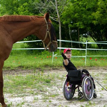 Young man in wheelchair working with horse at Viola Majewska's hippotherapy stable. Opening Our Eyes Movie.