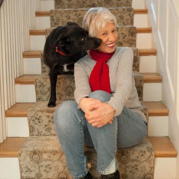 Mature woman at home on stairway with black dog